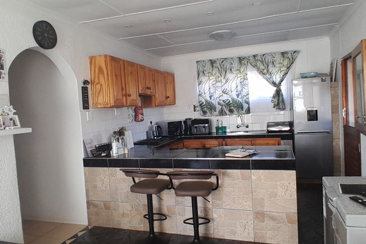 A functional kitchen featuring wooden cabinetry, a tiled breakfast bar, and integrated sink, offering a practical layout for daily meal preparation.