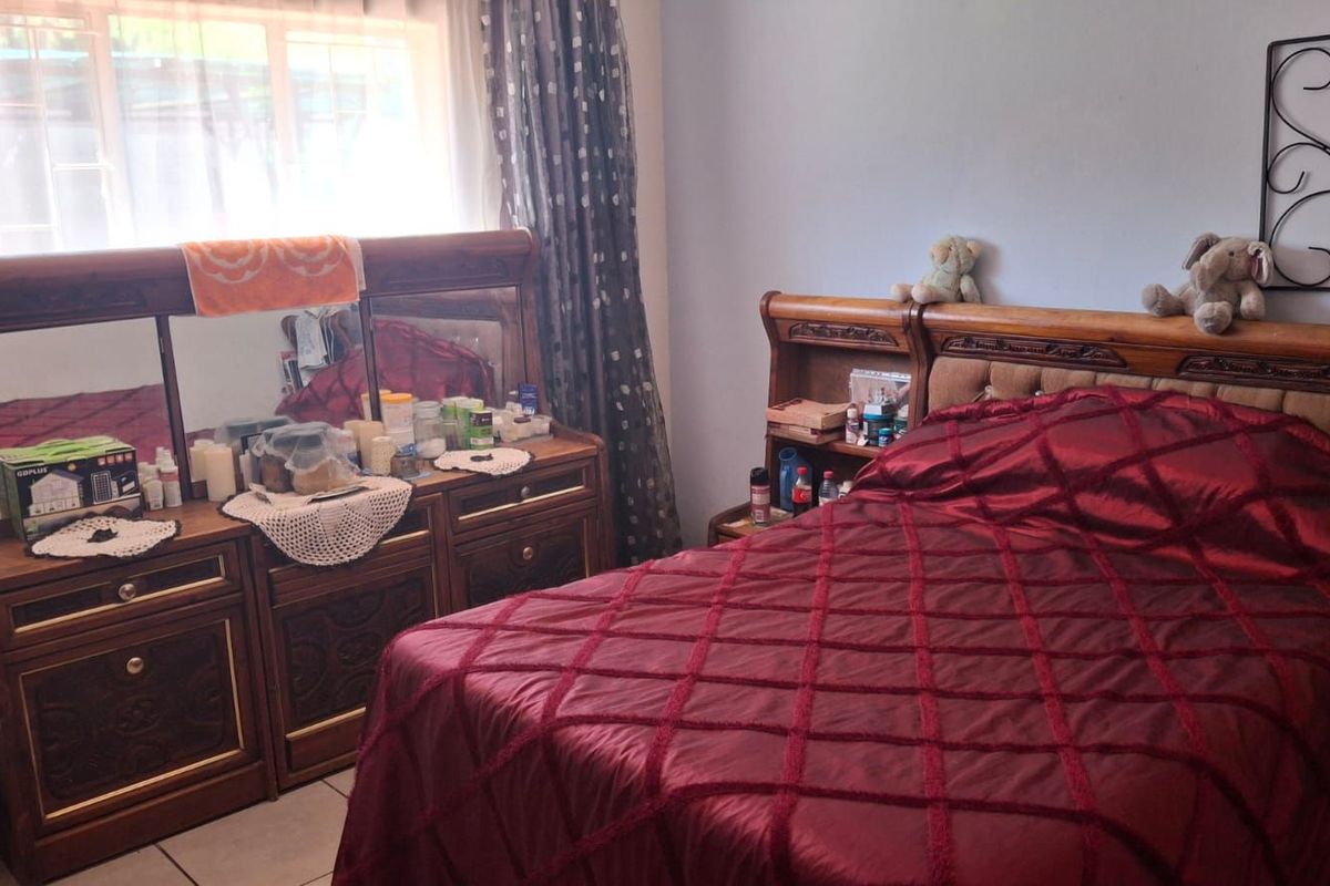 A bedroom featuring tiled flooring and a window with curtains.