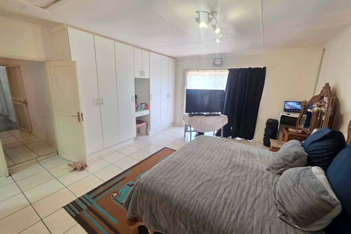 Spacious bedroom featuring extensive built-in white cabinetry, tiled flooring, and a ceiling-mounted light fixture.