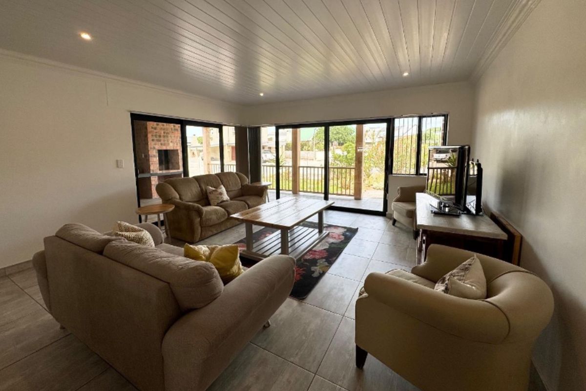 Spacious living room featuring large sliding glass doors that open to an outdoor patio area, tiled flooring, and recessed ceiling lighting.