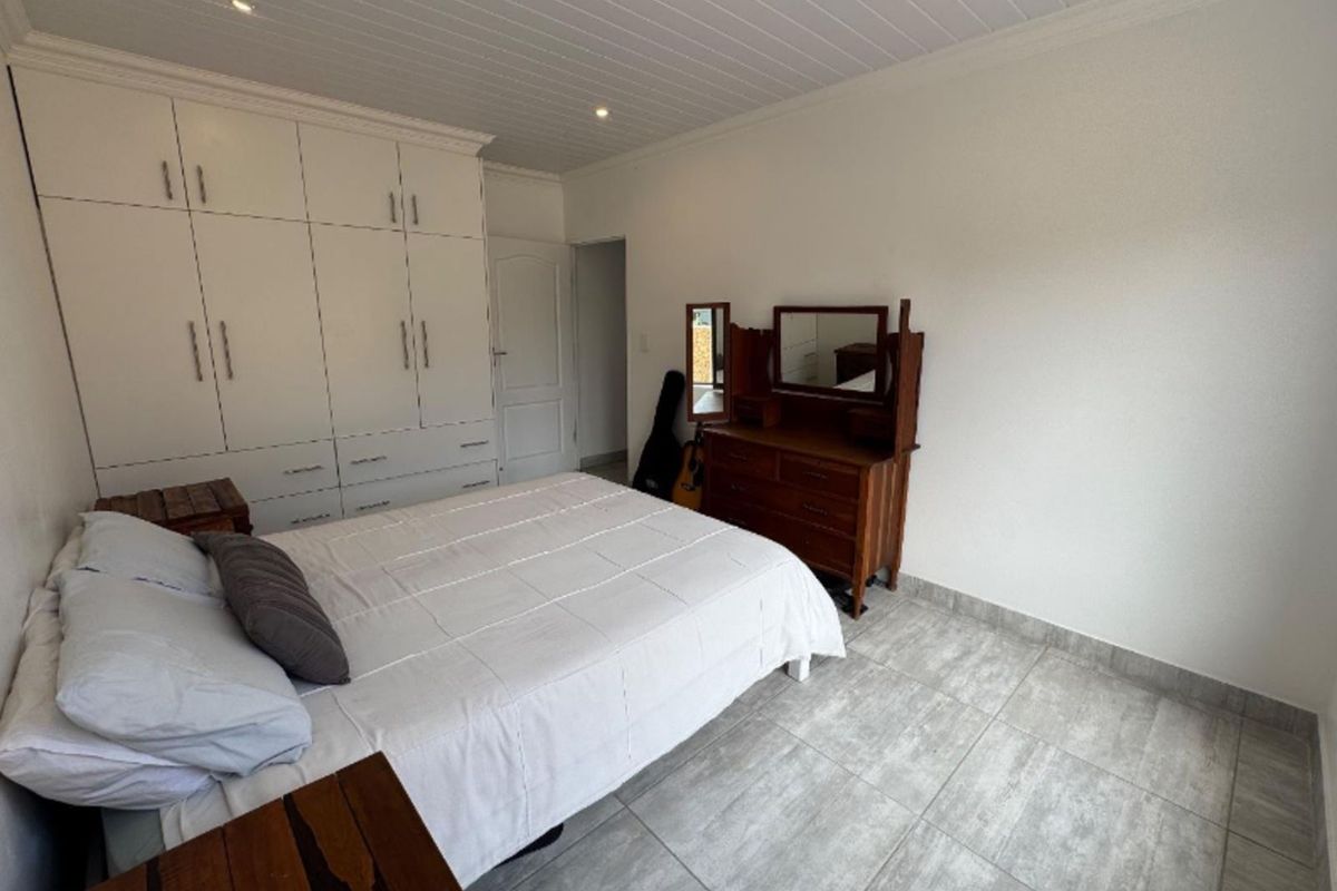 A well-maintained bedroom featuring built-in floor-to-ceiling cabinetry, tiled flooring, and a classic tongue-and-groove ceiling finish.