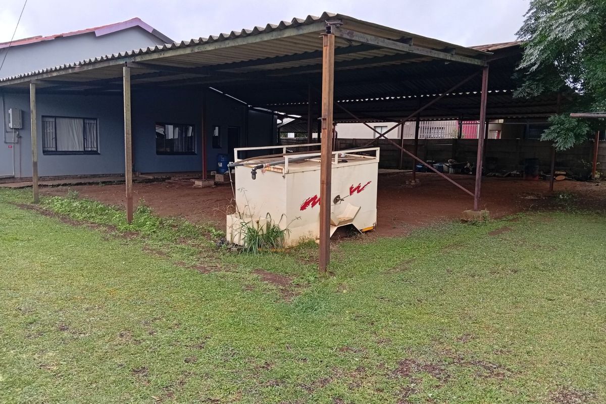A large outdoor covered area featuring a metal roof structure supported by steel posts, adjacent to the main house exterior.