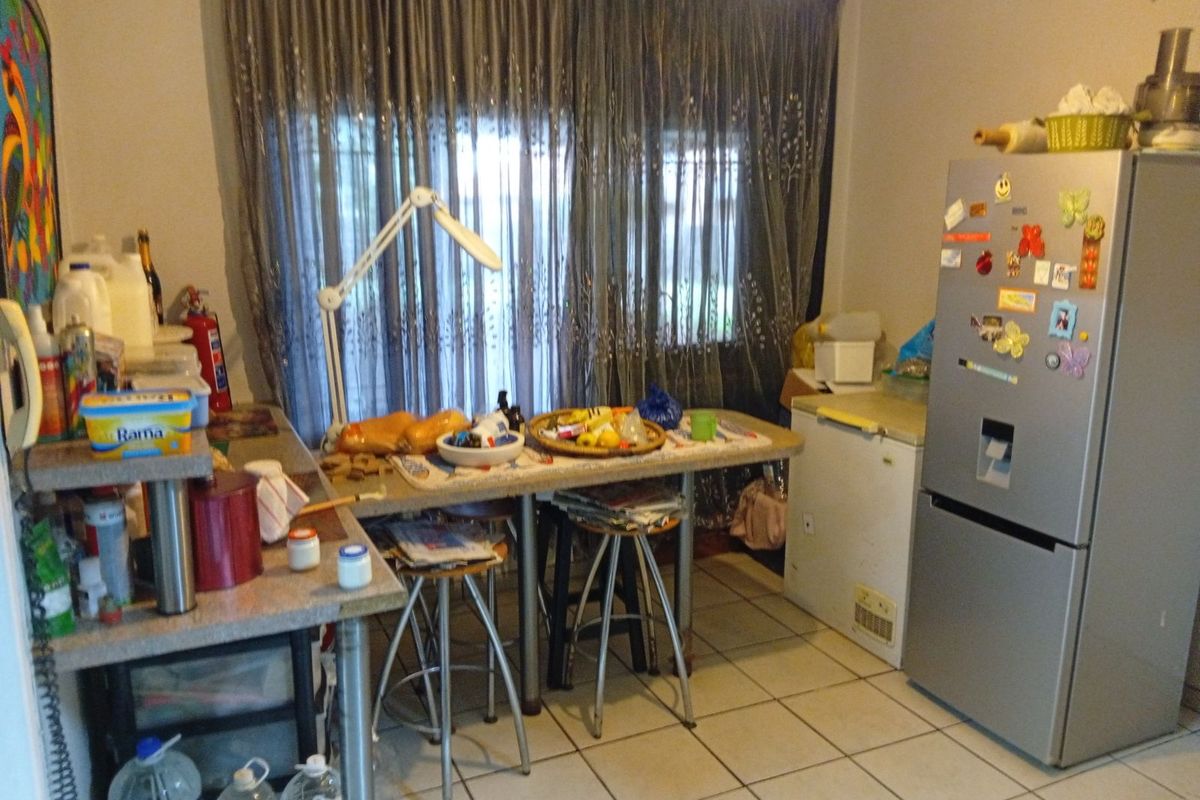 A functional kitchen area featuring tiled flooring, built-in counter space, and direct access to a window with curtain treatments.