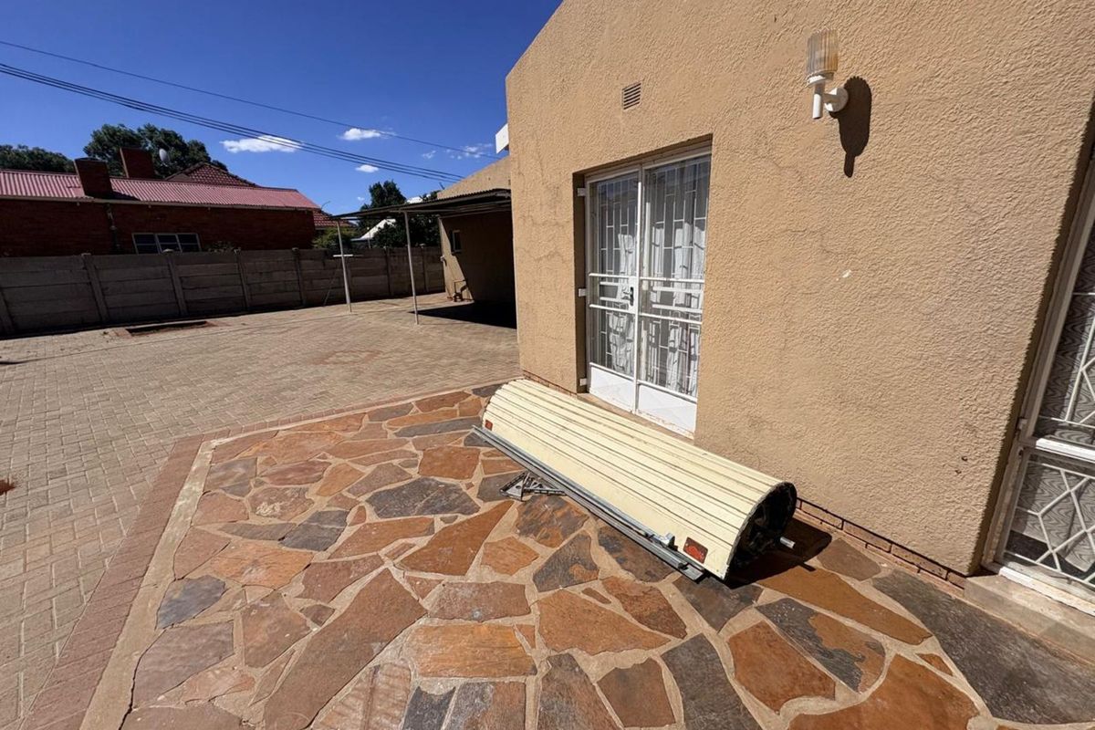 Rear exterior view of the property featuring a paved patio area, stone flooring, and access to the home via a sliding glass door.