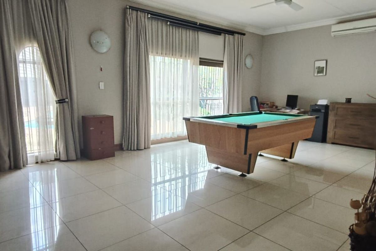 Spacious living area featuring large format floor tiles, sliding glass doors with curtain tracks, and a wall-mounted air conditioning unit.