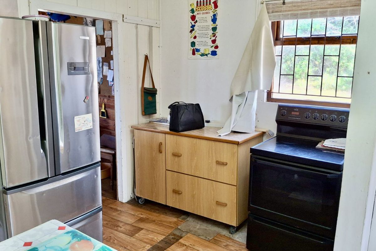 A functional kitchen area featuring a freestanding stove, mobile cabinetry unit, and wood-look flooring, providing a practical space for meal preparation.