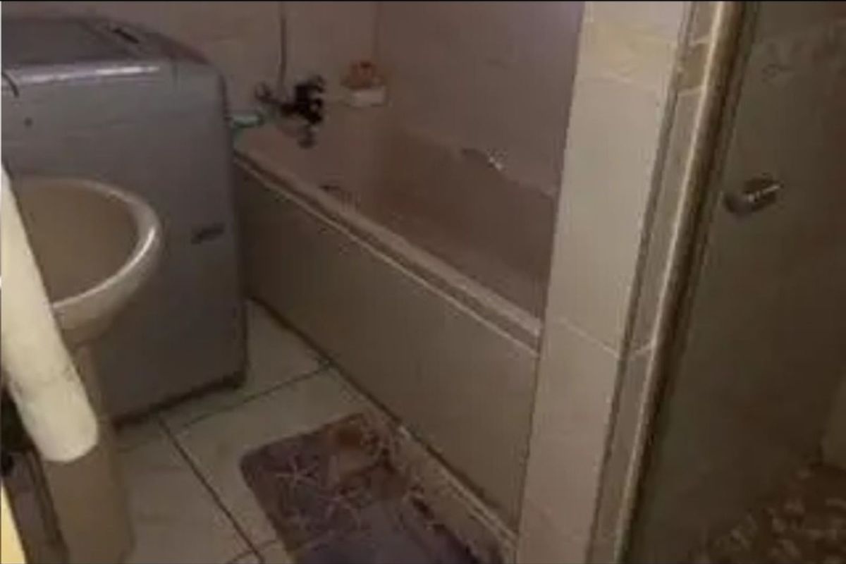 A compact bathroom featuring a built-in bathtub, pedestal sink, and tiled flooring, requiring modernization to improve its overall aesthetic and functionality.