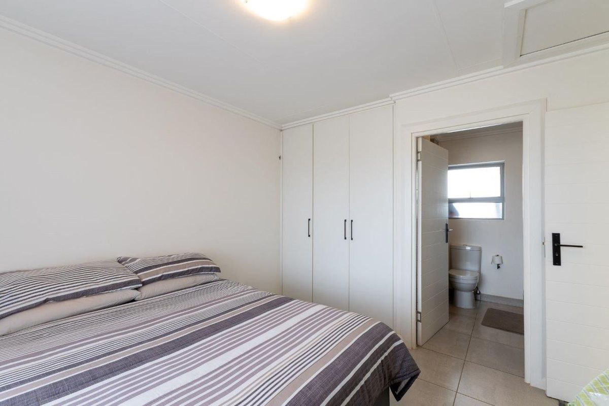 A bedroom featuring built-in cupboards and an en-suite bathroom with tiled flooring.