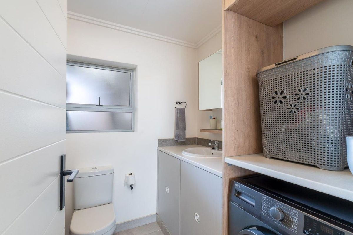 A functional bathroom featuring a built-in vanity with a basin, a toilet, and a dedicated space for a washing machine.