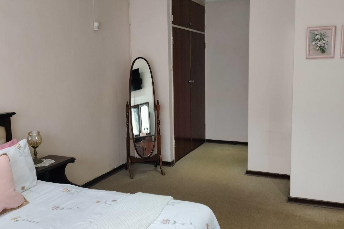 A bedroom featuring neutral walls, recessed ceiling lighting, and built-in wooden cupboards with carpeted flooring.