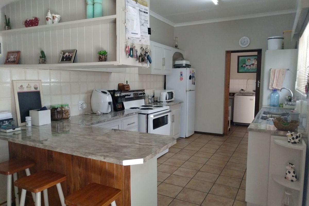 A functional kitchen featuring a breakfast bar, tiled countertops, built-in cabinetry, and an adjacent laundry area.