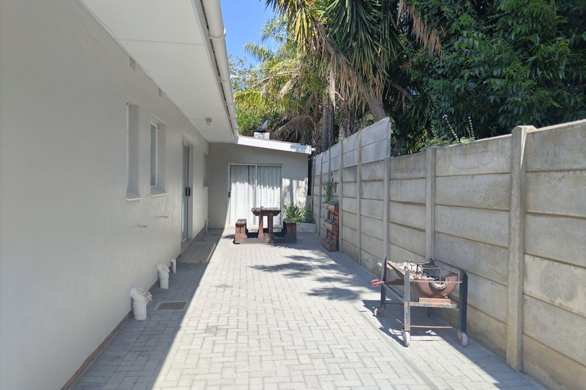 A paved rear patio area featuring a precast concrete boundary wall and direct access to the main dwelling.