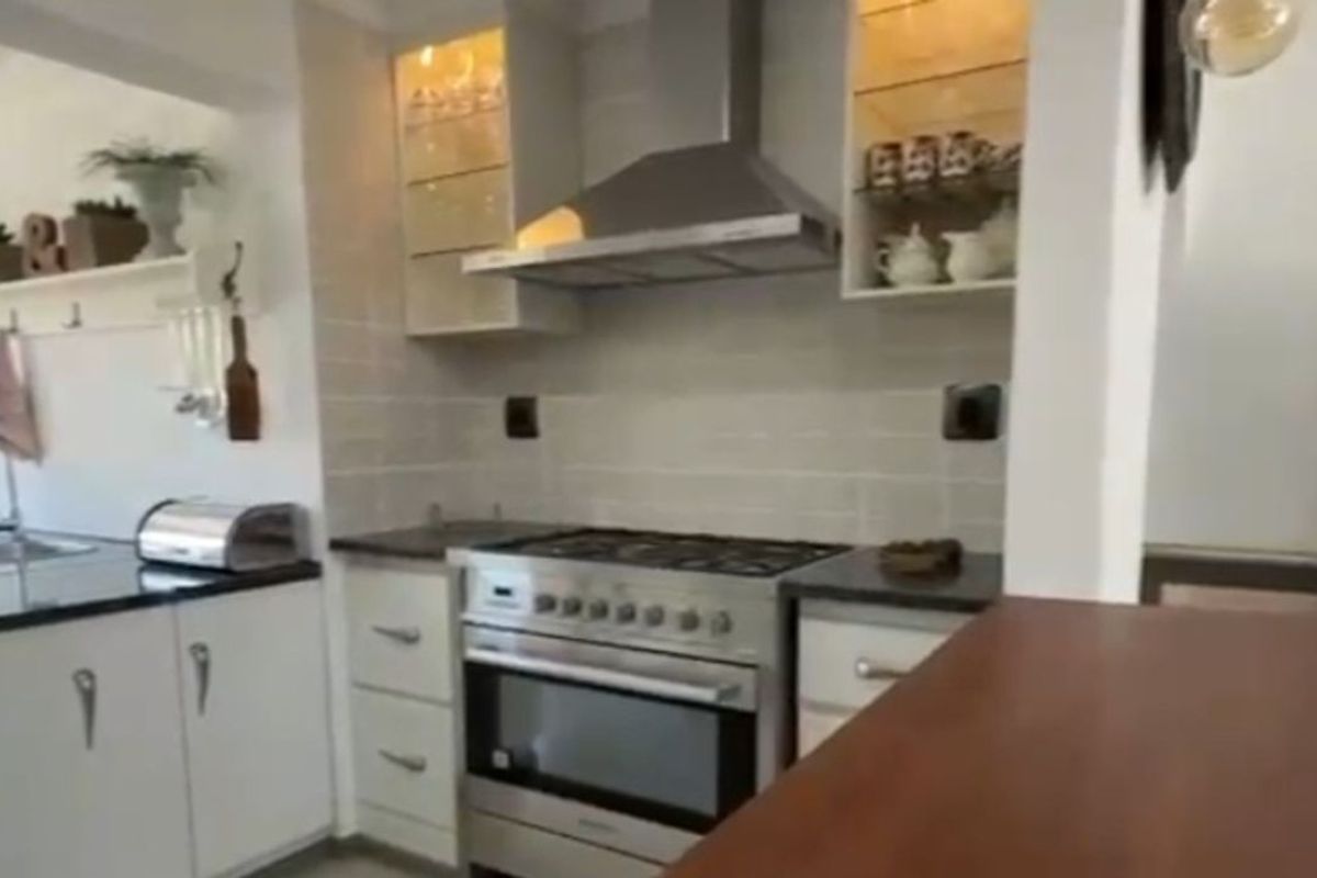 A functional kitchen featuring white cabinetry, dark countertops, a stainless steel gas stove with extractor fan, and tiled backsplash.
