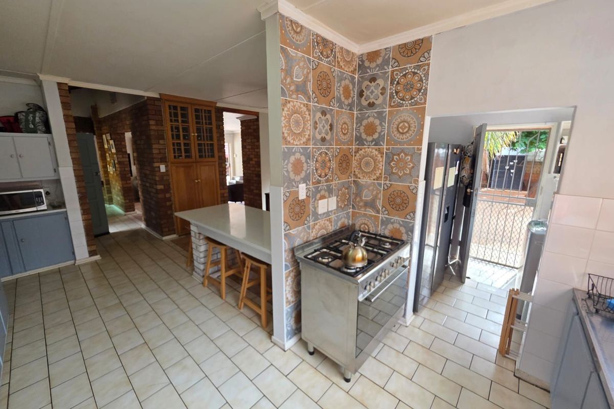 A functional kitchen featuring a freestanding gas stove, decorative tiled splashback, built-in breakfast counter, and direct access to the exterior.
