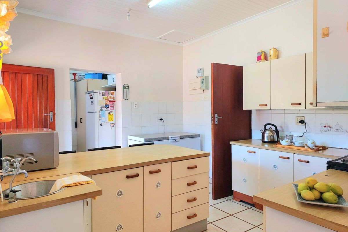 A functional kitchen featuring laminate countertops, built-in cabinetry, tiled flooring, and a convenient adjacent scullery area.