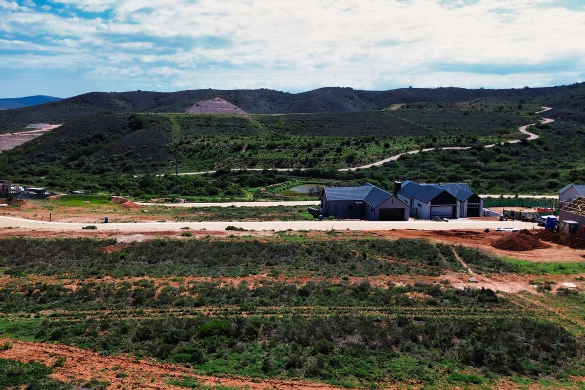 An aerial view of a residential property under development, showcasing the surrounding landscape and natural terrain.