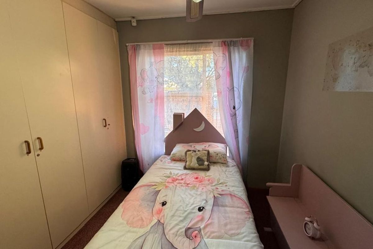 A bedroom featuring built-in floor-to-ceiling cupboards and a window with natural light.