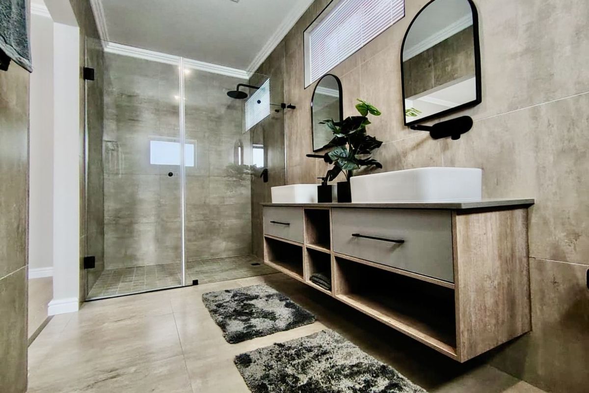 Modern bathroom featuring a floating double vanity with vessel sinks, large walk-in glass shower, and contemporary neutral wall tiling.