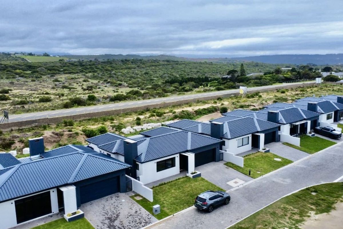 Aerial view of a modern residential estate featuring contemporary homes with dark metal roofs, paved driveways, and landscaped front gardens.