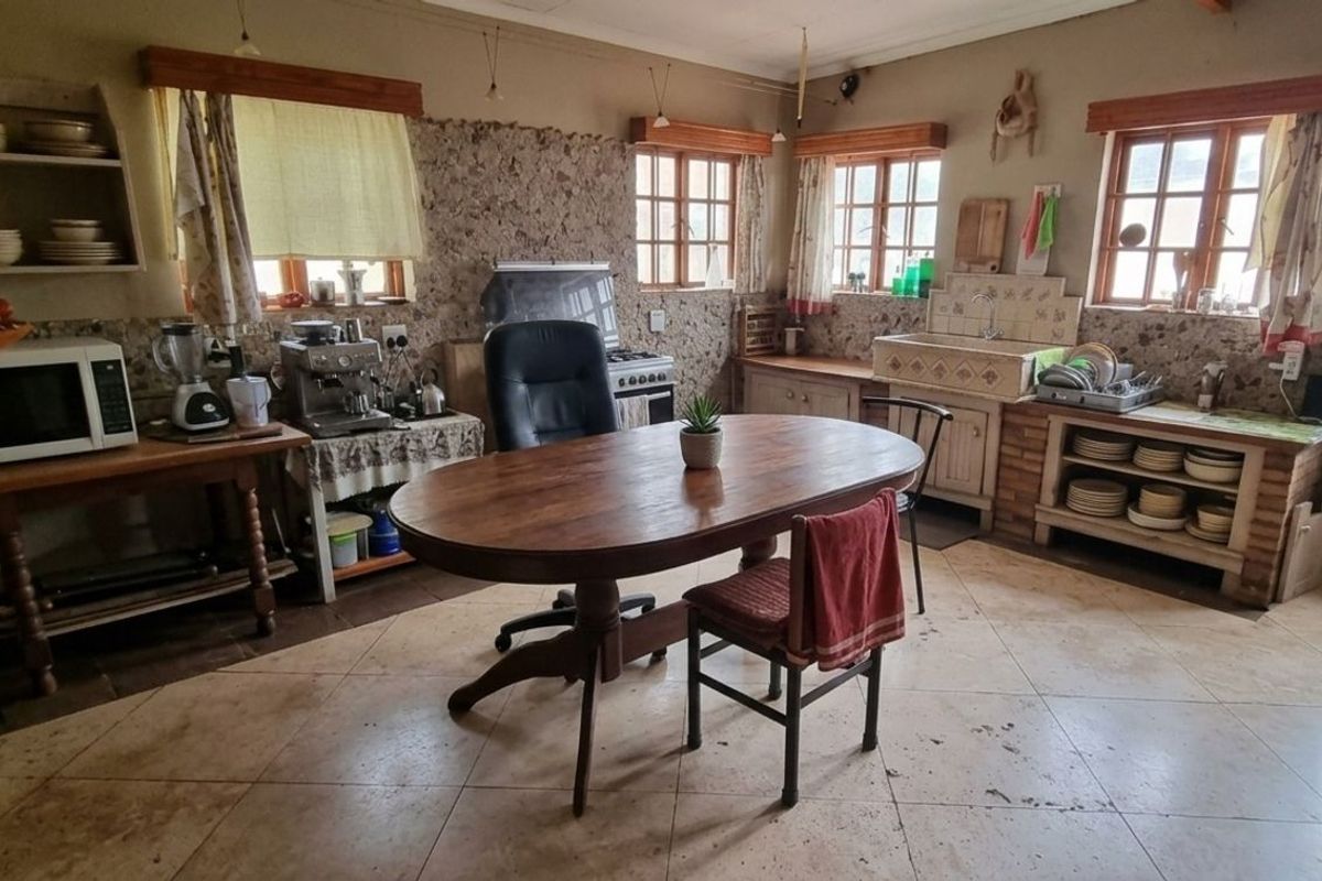 A rustic-style kitchen featuring stone-textured walls, tiled flooring, a farmhouse-style sink, and wooden window frames, offering a warm and traditional aesthetic.
