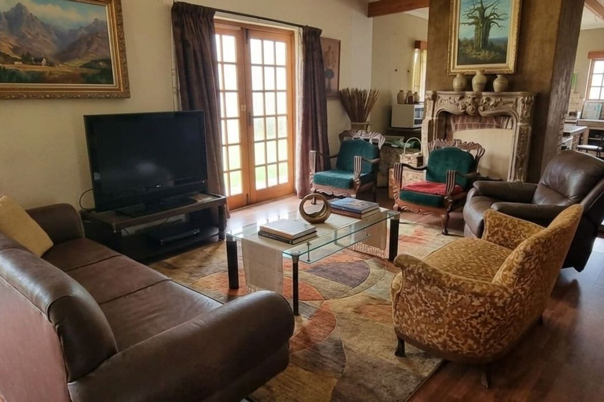 A cozy living room featuring a prominent stone fireplace, wooden flooring, and French doors leading to the exterior.