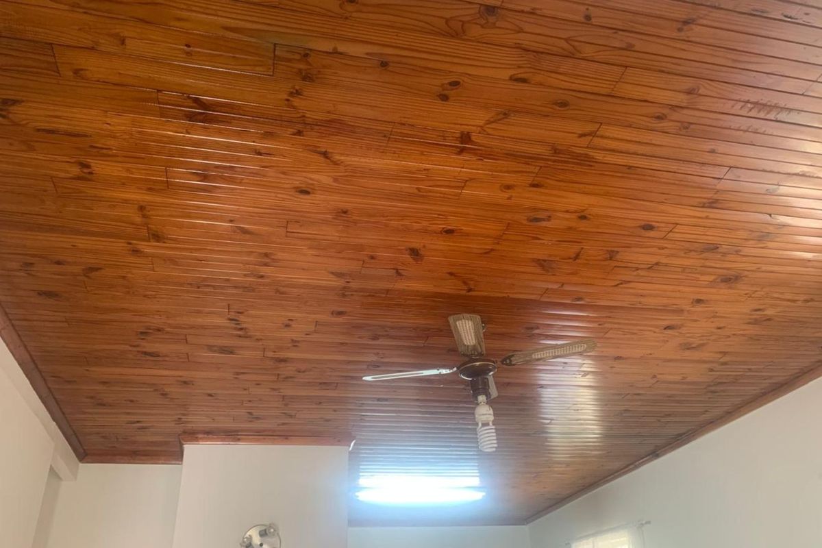 Interior view of a room featuring a varnished wooden tongue-and-groove ceiling with a central ceiling fan.