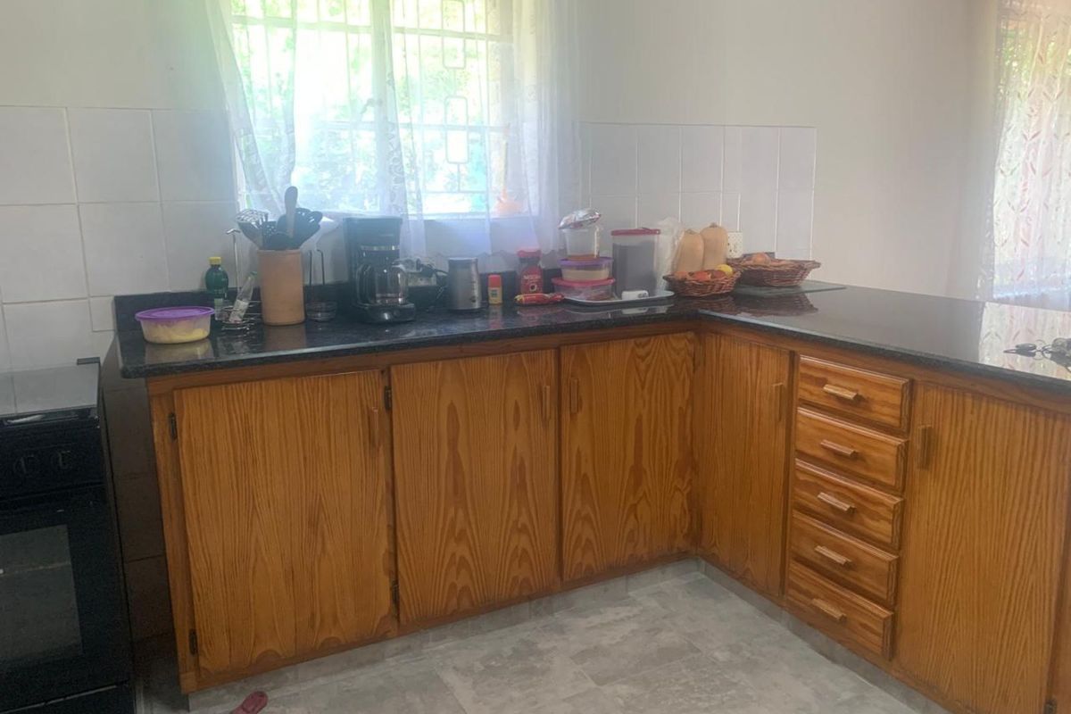 A functional kitchen featuring wooden cabinetry, dark granite countertops, tiled splashbacks, and a built-in oven.