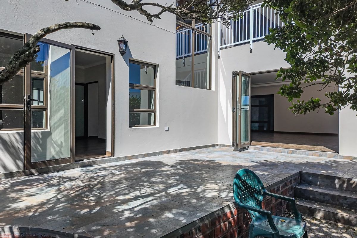 A spacious rear patio area featuring tiled flooring, large glass sliding doors, and direct access to the interior living spaces.