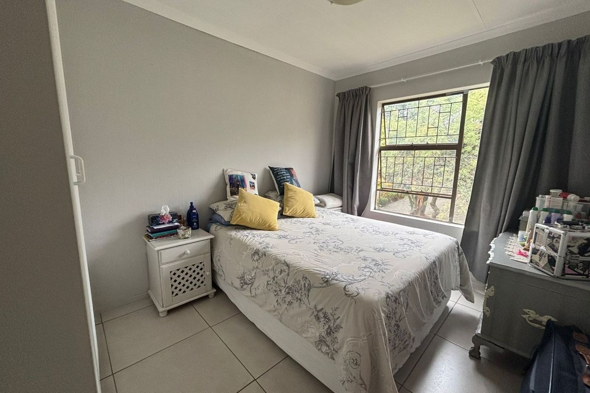 A bedroom featuring tiled flooring, a window with security bars, and neutral wall finishes.