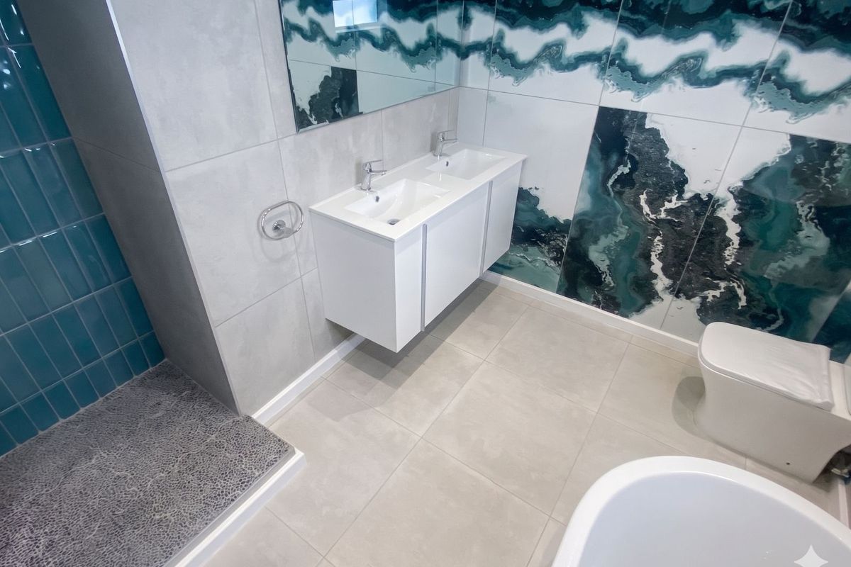 Modern bathroom featuring a double vanity, walk-in shower with textured tiling, and a freestanding bathtub with striking decorative wall tiles.