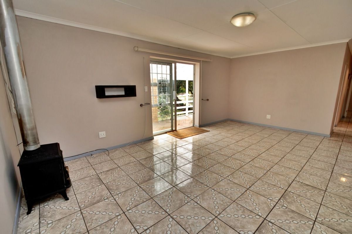 An empty living room featuring tiled flooring, a built-in wood-burning fireplace, and sliding glass doors providing access to the outdoor area.