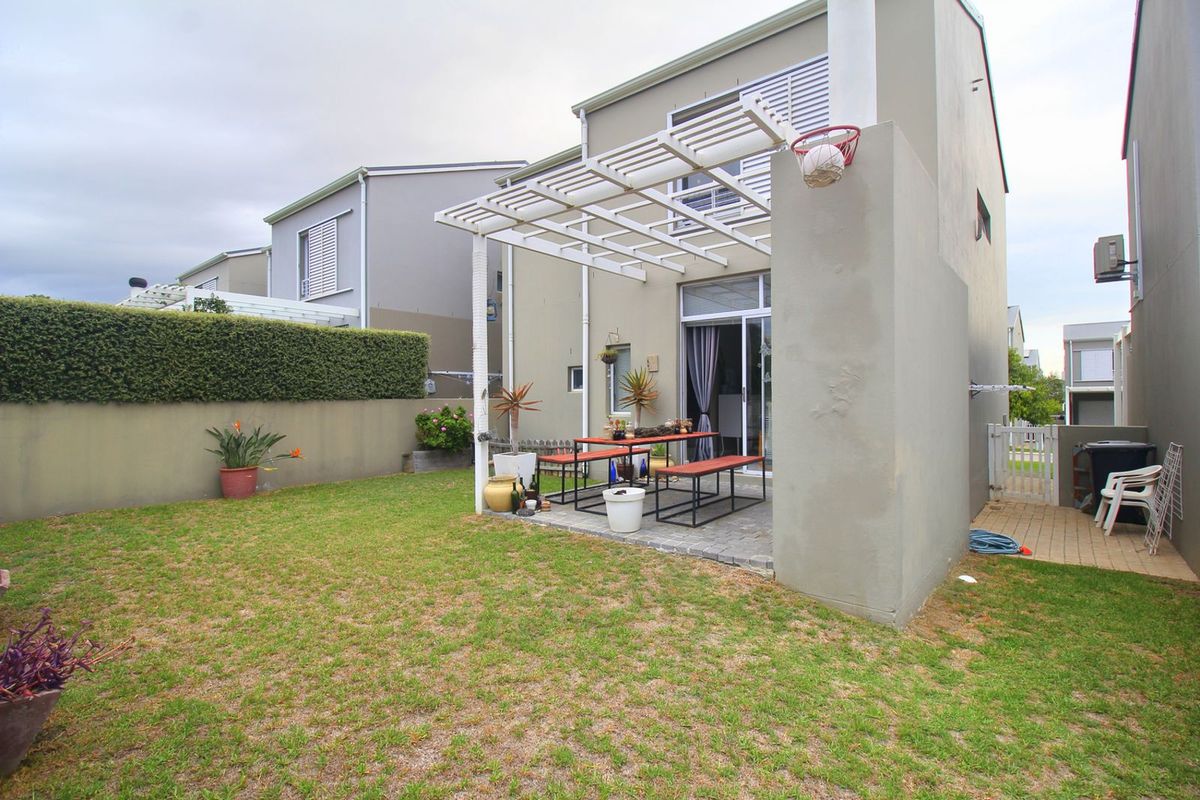 Rear view of the townhouse featuring a paved patio area with a pergola, a private garden, and sliding glass door access.