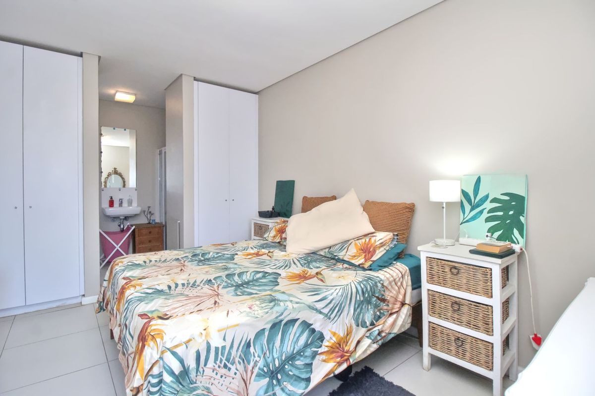 A bright bedroom featuring built-in floor-to-ceiling wardrobes and an integrated en-suite vanity area with tiled flooring.