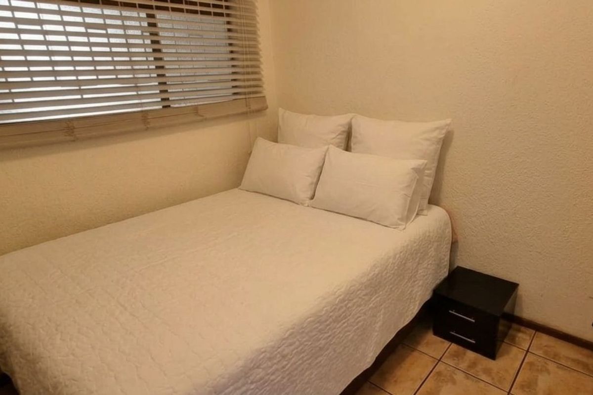 A compact bedroom featuring tiled flooring and horizontal window blinds.