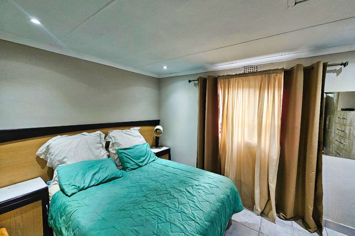 A functional bedroom featuring tiled flooring, recessed ceiling lighting, and built-in headboard cabinetry.