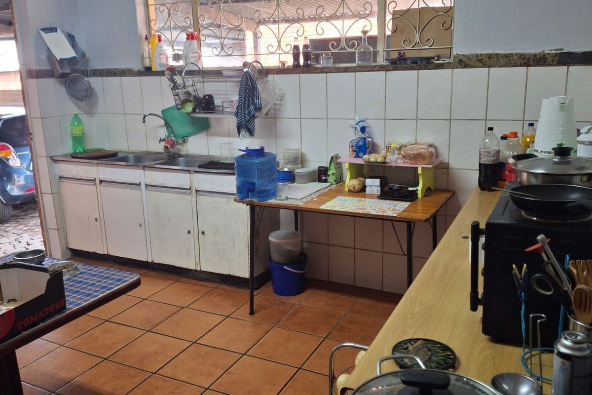 A functional kitchen area featuring tiled flooring, built-in cabinetry, and a double sink, with direct access to an outdoor area.
