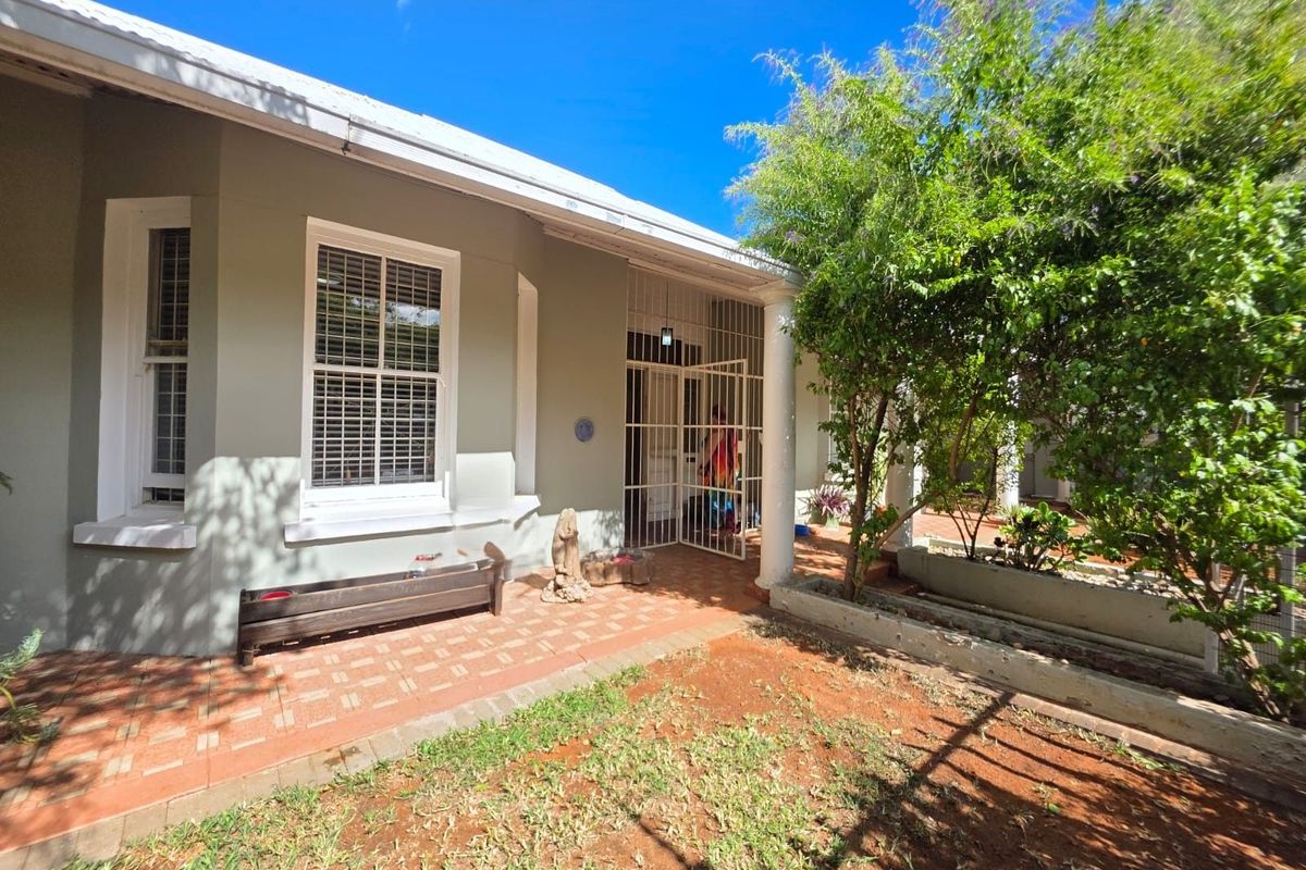 A view of the rear exterior of the house featuring a covered patio area, tiled flooring, and access to the garden.