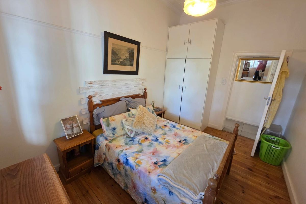 A bedroom featuring original timber flooring, built-in cabinetry, and classic picture rails, offering a traditional and cozy living space.
