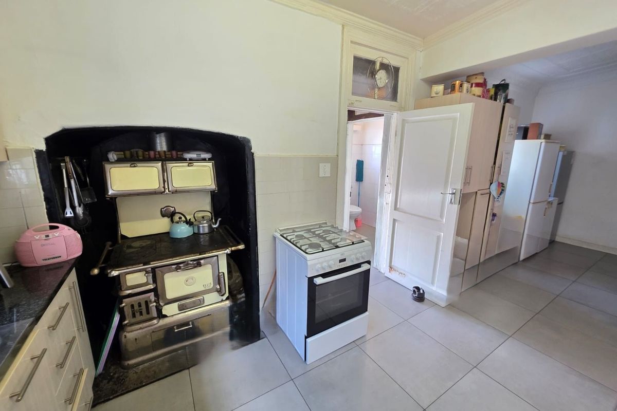 Kitchen featuring a vintage-style built-in stove, modern freestanding gas cooker, tiled flooring, and direct access to an adjacent room.