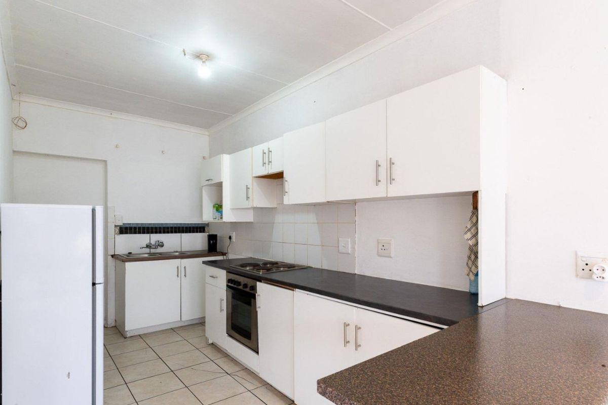 Functional kitchen featuring white cabinetry, dark laminate countertops, built-in oven, hob, and tiled flooring.