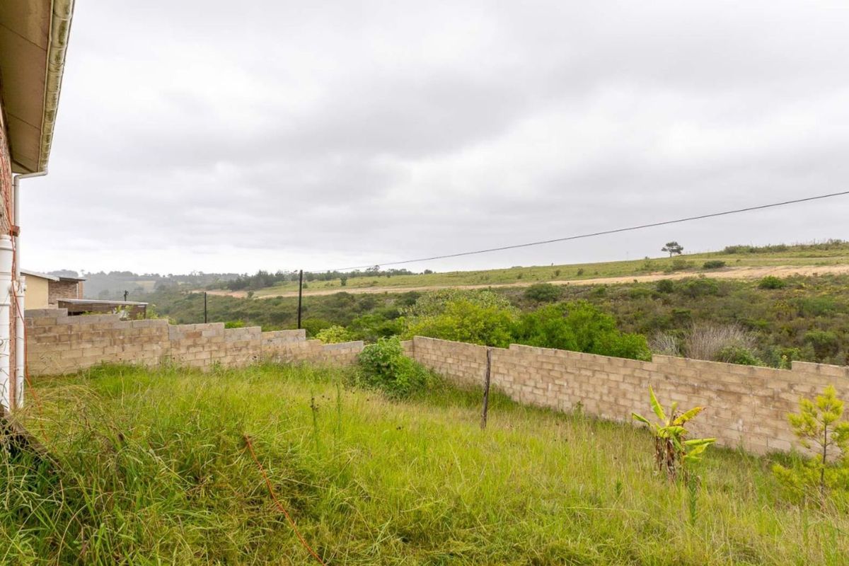 A view of the rear yard featuring an unfinished brick boundary wall and expansive natural landscape views.