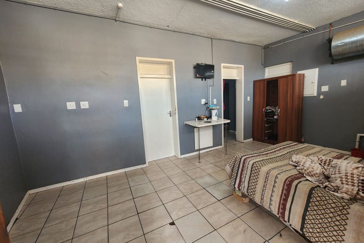 A bedroom featuring tiled flooring, surface-mounted electrical conduits, and multiple doorways leading to adjacent areas.