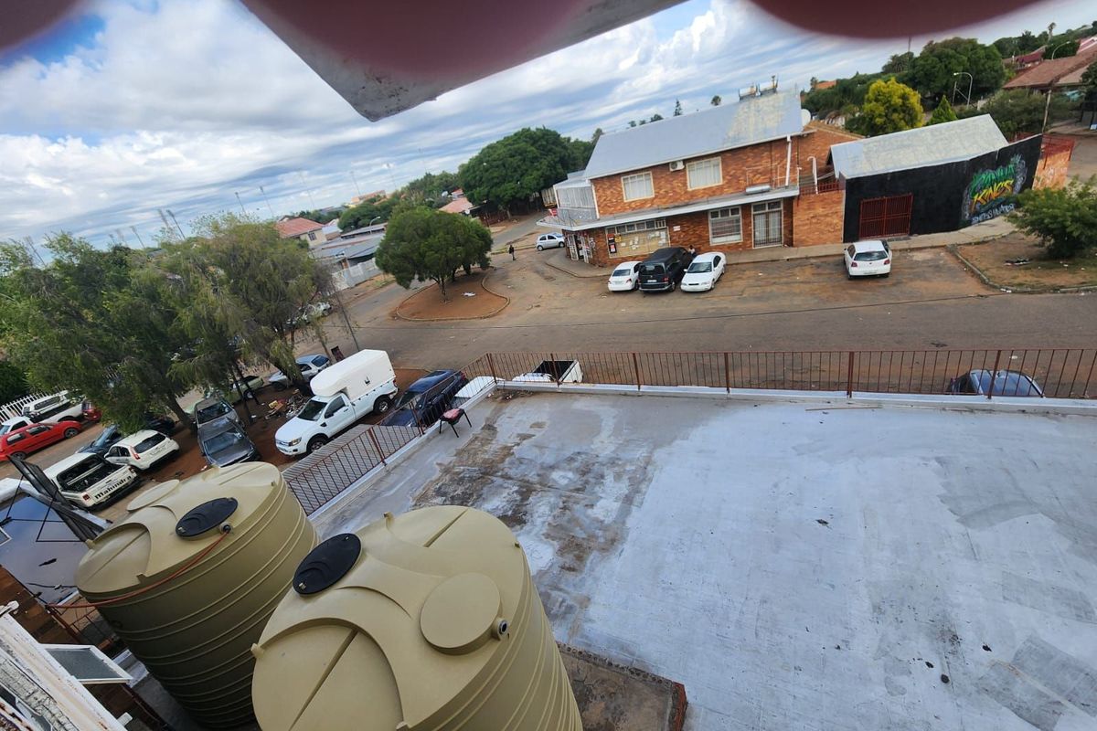 Elevated view of the property rooftop featuring large water storage tanks, overlooking the street and surrounding commercial area.