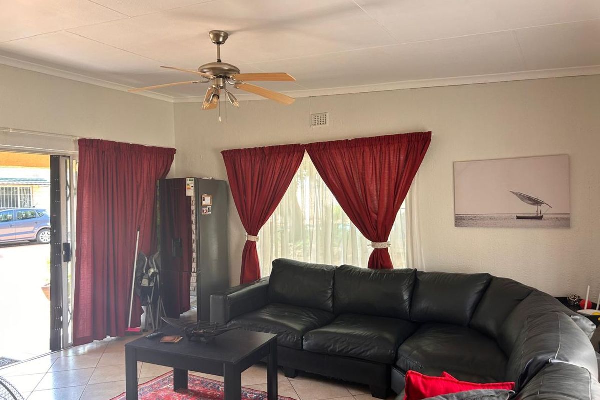 A living room featuring tiled flooring, a ceiling fan, and sliding glass doors providing access to the exterior.