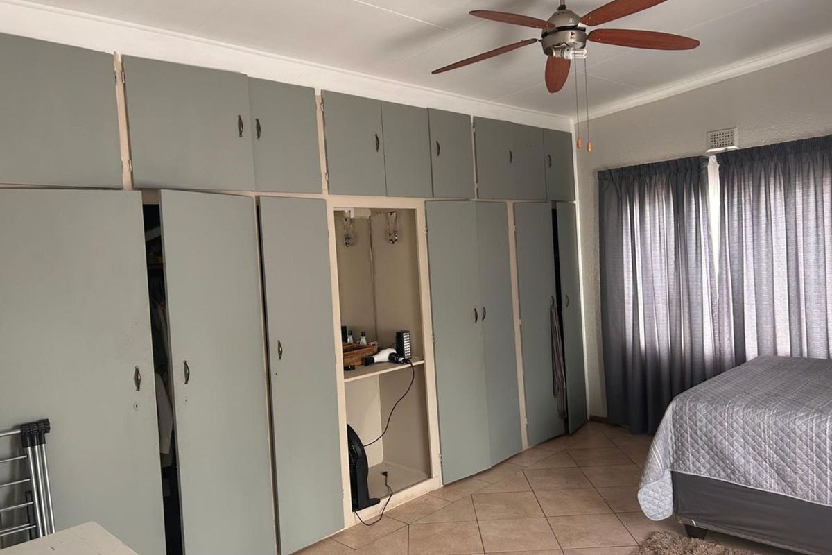 Bedroom featuring extensive built-in cabinetry with integrated shelving and a ceiling fan, finished with tiled flooring.
