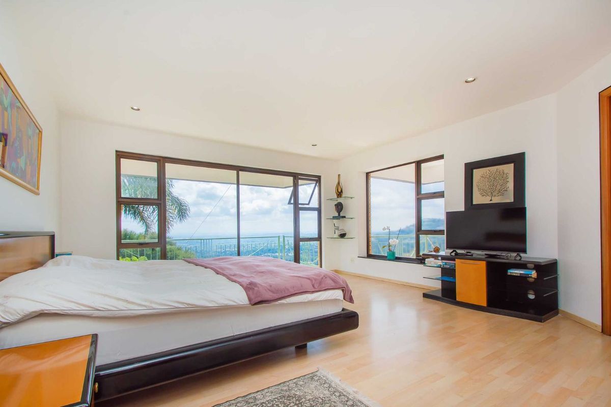 Spacious bedroom featuring large windows with panoramic views, light wood flooring, and recessed ceiling lighting.
