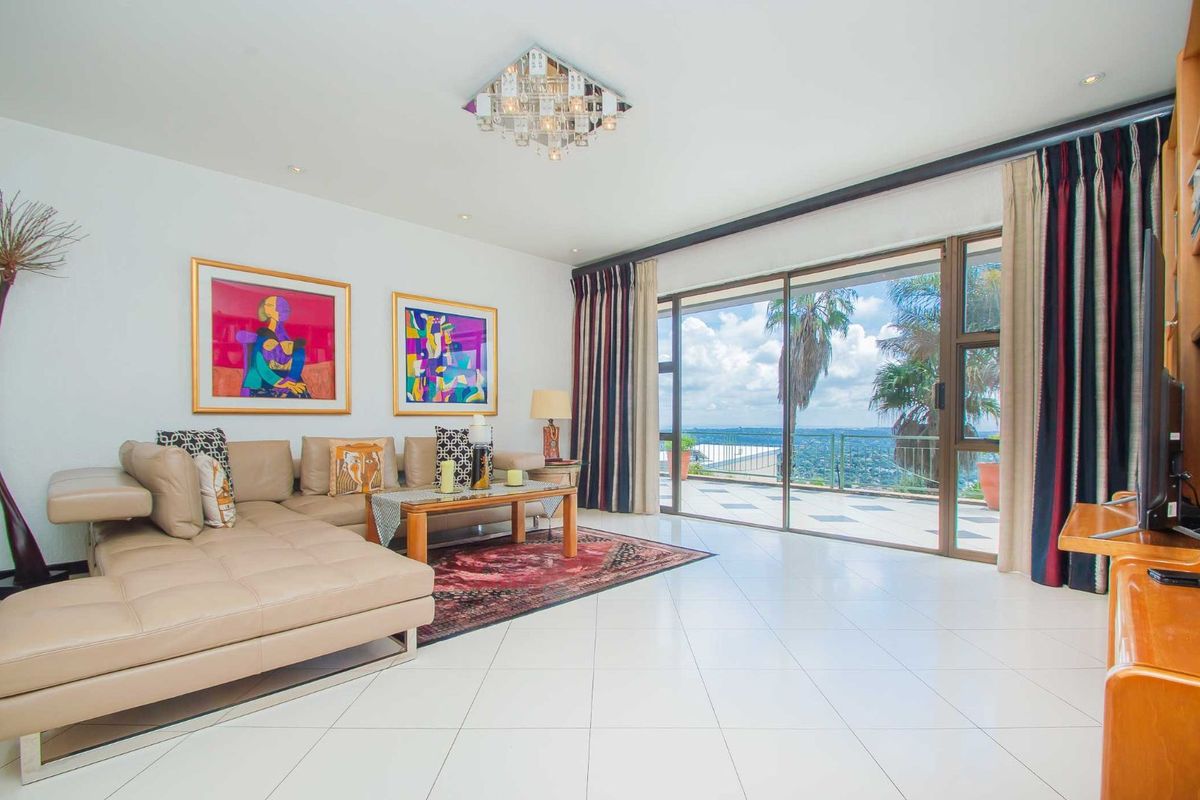 Spacious living room featuring large sliding glass doors that open onto a balcony with expansive scenic views and polished tile flooring.