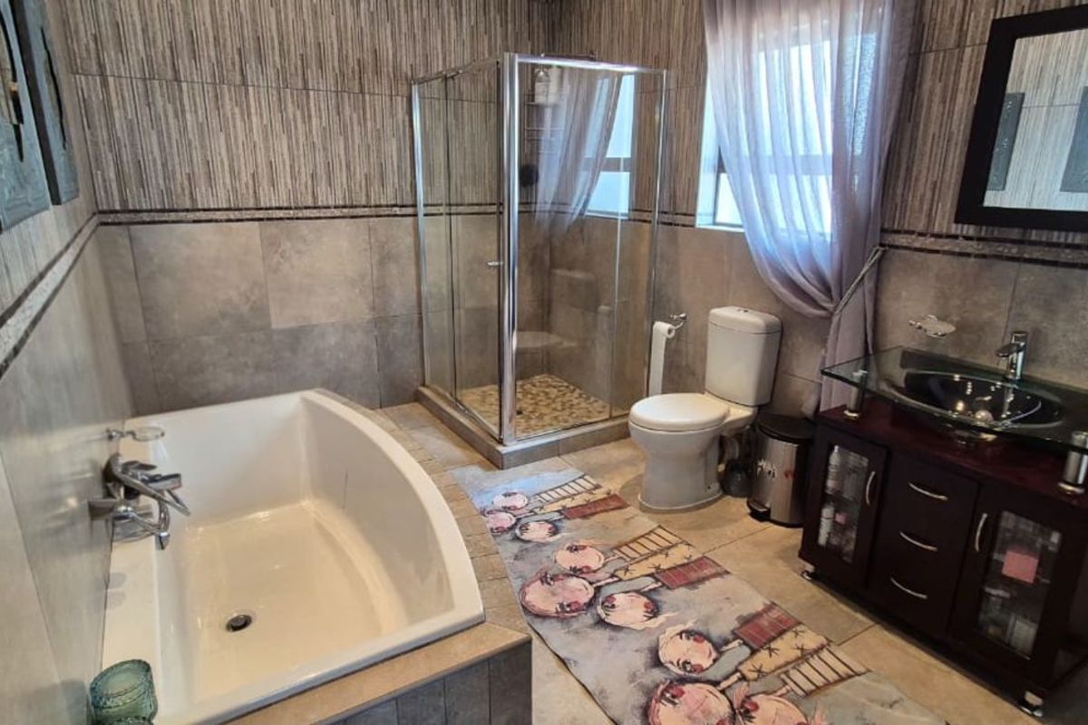 A well-appointed bathroom featuring a built-in bathtub, a glass-enclosed shower, a vanity with a vessel sink, and full-height wall tiling.