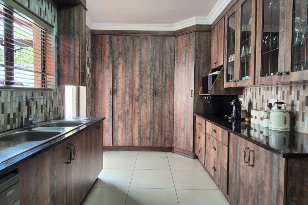 A well-maintained kitchen featuring dark wood-grain cabinetry, granite countertops, mosaic tile backsplash, and tiled flooring with ample storage space.