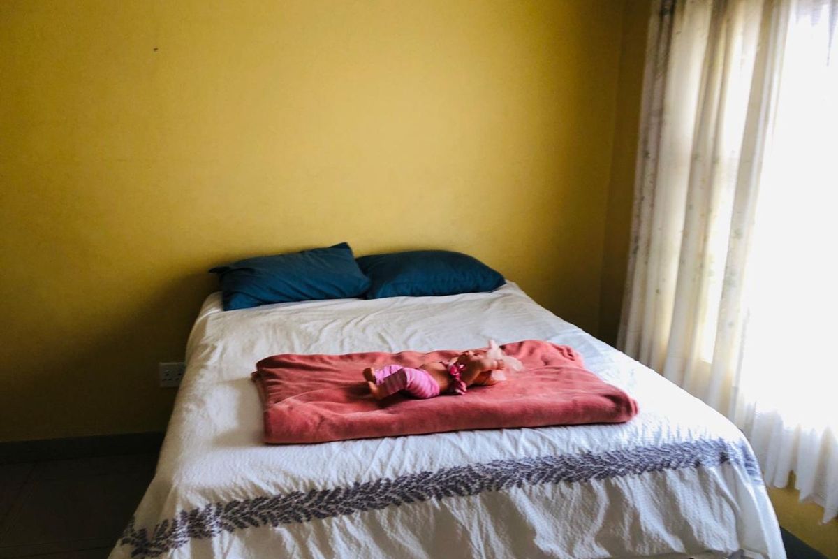 A bedroom featuring yellow painted walls, tiled flooring, and a window with curtains.